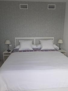 uma cama branca com 2 almofadas brancas e 2 candeeiros em Great views terrace apartment em Torremolinos