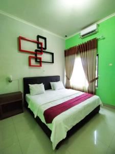 een slaapkamer met een bed met groene muren en een raam bij RedDoorz at Hotel Nuansa Ngawi in Ngawi