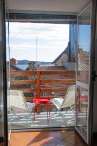 een rode stoel en 2 stoelen op een balkon bij Casa Zeda - WelcHome in Verbania