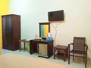 een kamer met een bureau, een stoel en een tv bij RedDoorz at Hotel Nuansa Ngawi in Ngawi