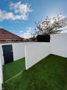 una cerca blanca con un patio con césped verde en Pier Plain By The Sea en Gorleston-on-Sea