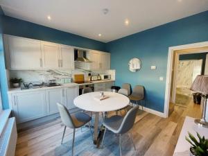 a kitchen with blue walls and a table and chairs at Pier Plain By The Sea in Gorleston-on-Sea