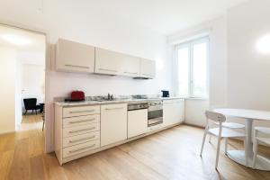 米蘭的住宿－Contempora Apartments - Turati 3 One Bedroom Apartment，白色的厨房配有白色的橱柜和桌子
