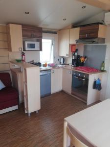 una pequeña cocina con armarios blancos y electrodomésticos azules en Grand Mobil home 3chbr 2sdb camping La Carabasse en Vias