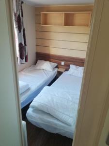 two beds in a small room with a doorway at Grand Mobil home 3chbr 2sdb camping La Carabasse in Vias