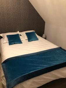 a large bed with two blue pillows on it at Les gîtes de Joséphine in Courbouzon