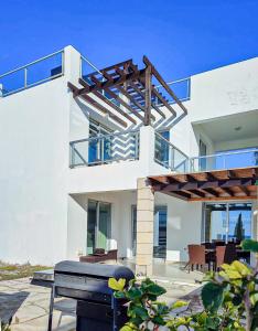 een wit huis met een patio met een grill bij 3 Bedroom Seaview Villa direct in Coral Bay with Pool in Coral Bay