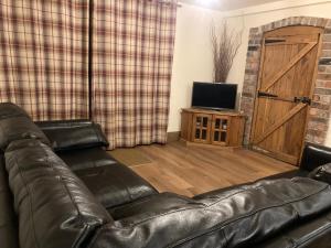 a leather couch in a living room with a sliding door at Stylish Ground Floor apartment at Pingle Nook Farm in Denby Dale