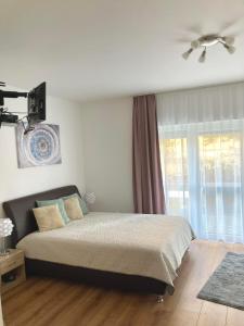 sypialnia z łóżkiem i dużym oknem w obiekcie Jade Apartman w Hévízie
