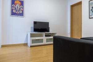 a living room with a television on a white cabinet at Entrecampos - Family apartment with Terrace in Lisbon