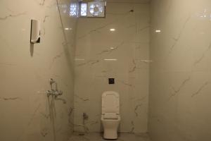 a white bathroom with a toilet and a shower at RAJWADA RESORT & HOTEL in Raipur
