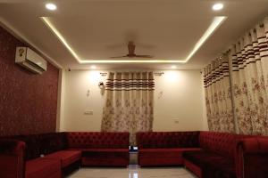 una sala de espera con sofás y cortinas rojos en RAJWADA RESORT & HOTEL, en Raipur
