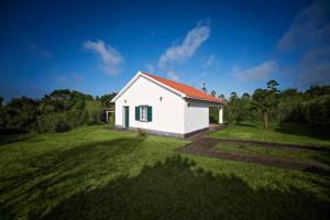 a small white house with a red roof on a grass field at Garden Oasis in Capelo