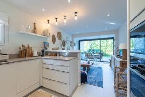 a kitchen with white cabinets and a large window at LA PAUSA, Maison de ville avec Jardin centre de SAINT TROPEZ in Saint-Tropez