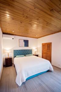 a bedroom with a large bed with a wooden ceiling at Garden Oasis in Capelo