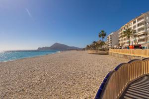 a beach with benches and palm trees and the ocean at PÌSO MAR ALTEA in Altea