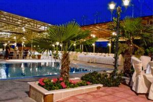 ein Schwimmbad mit Palmen und Blumen in einem Gebäude in der Unterkunft Asteras Hotel in Náousa (Imathia)