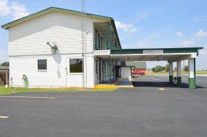 a white building with a parking lot in front of it at Travel Inn Weatherford in Weatherford