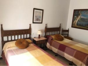 1 dormitorio con 2 camas y mesa con lámpara en SANTA ANA en Es Castell