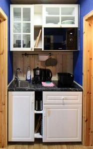 eine Küche mit weißen Schränken und einem Waschbecken in der Unterkunft Fewo DUE in Naundorf