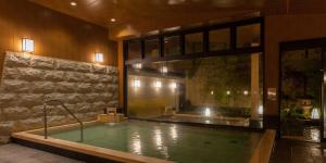 a large swimming pool in a building with a large window at Nishitetsu Resort Inn Beppu in Beppu