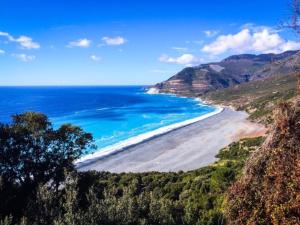 a view of a beach with the ocean and mountains at Location Cap corse in Canari