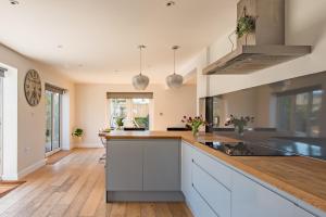 a kitchen with white cabinets and a wooden floor at The George - Large family home by the sea in Deal