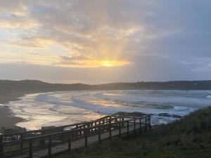 a sunset over the ocean with a wooden bridge at Village Way Apartments in Kincasslagh