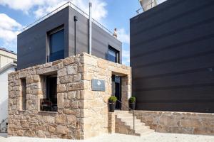 a black house with a stone wall at Casas do Patio Country Houses & Nature in Caldas da Felgueira