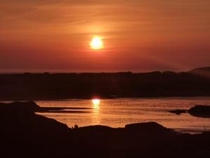 a sunset over the water with the sun in the sky at Village Way Apartments in Kincasslagh