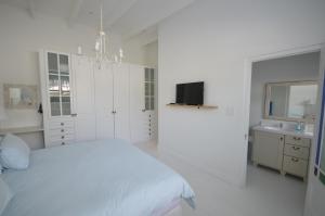 een witte slaapkamer met een bed en een wastafel bij Willow Cottage in Kaapstad