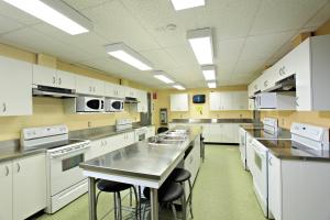 a large kitchen with white cabinets and appliances at Residence & Conference Centre - Sudbury West in Sudbury