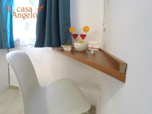 białe krzesło siedzące na drewnianej półce w pokoju w obiekcie Casa Angelo B&B w mieście Calasetta