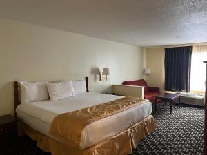 a hotel room with a bed and a chair at Budgetel Inns & Suites in Fairfield