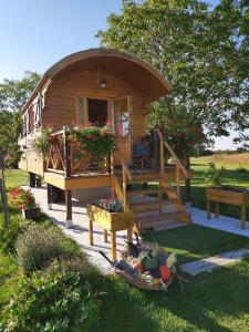 uma cabana de madeira com um alpendre e uma mesa de vegetais em LA ROULOTTE DE FLORETTE em Soings-en-Sologne