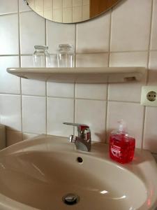 - un lavabo avec une bougie rouge et des verres sur une étagère dans l'établissement Ferienwohnung am Kirschbaum, à Uhldingen-Mühlhofen