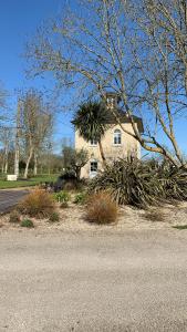 a house with a palm tree in front of a street at Gîte Vaugoubert in Saint-Germain-de-Varreville