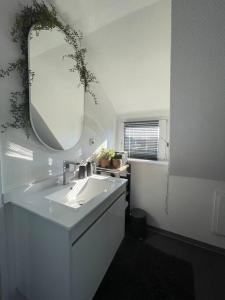 a white bathroom with a sink and a mirror at Gemütliche, helle Wohnung in Paderborn in Paderborn