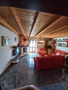 a living room with a red couch and a kitchen at casa vacanza da ghislin in Teglio