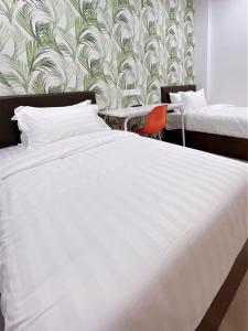 sypialnia z białym łóżkiem i tapetą w obiekcie Hotel Decentraland Kuala Terengganu w mieście Kuala Terengganu