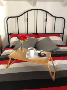 einen Tisch mit einer Blume und zwei Tassen auf einem Bett in der Unterkunft Gattaglio 22 Guest House in Reggio nell'Emilia