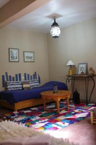 ein Wohnzimmer mit einem Bett und einem Tisch in der Unterkunft Au Bord de l'Eau in Setti Fatma