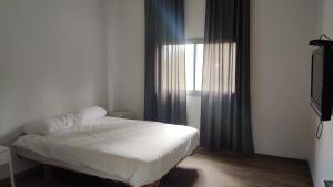 een slaapkamer met een wit bed en een televisie bij יערה בכפר קרוב לנחל in Bet Hillel