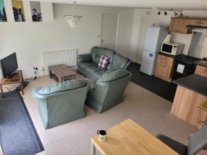 ein Wohnzimmer mit 2 Stühlen, einem Sofa und einem Tisch in der Unterkunft RentUnique Spinney SpaciousSuper Snug 1 bed home. in Ifield