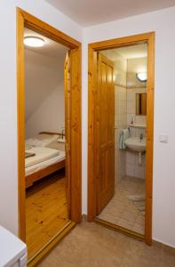 a room with a bathroom with a bed and a mirror at NOBLE'S Panzió és Étterem in Nemesnép