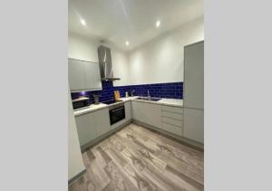 cocina con armarios blancos y suelo de madera en Doncaster City Centre Deluxe Whole Apartment sleeps 4 D19 en Doncaster