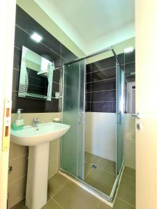 uma casa de banho com um lavatório e uma cabina de duche em vidro. em Appartment Lura 3 em Durrës