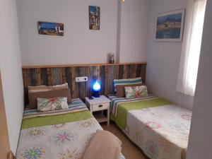 エル・カンページョにあるApartament Cala Merced Alicante El Campelloのベッド2台、ランプ1台が備わる客室です。