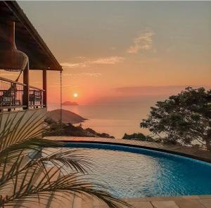 a swimming pool with a view of the ocean at sunset at Pousada La Belle Maison Brigitte Bardot in Búzios