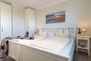 2 Betten in einem weißen Schlafzimmer mit einer Theke in der Unterkunft Apartmenthaus "Kiki", Wohnung "Traumbude" in Heiligenhafen